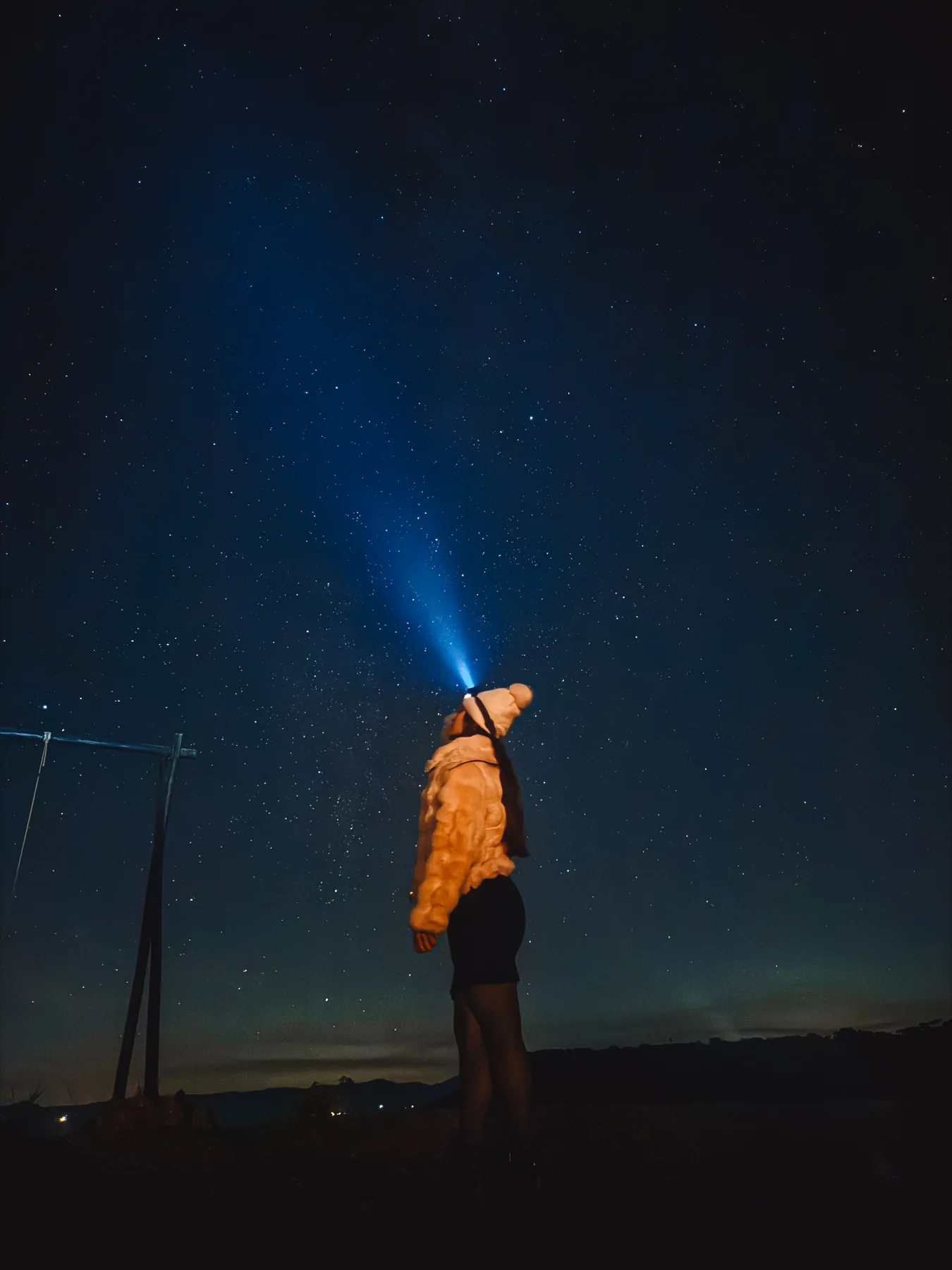 Pessoa com lanterna de cabeça olhando um céu estrelado